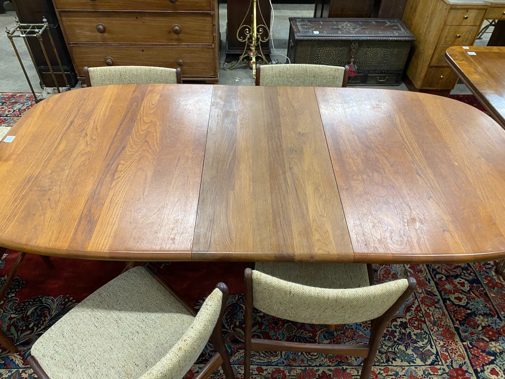 A mid century teak extending dining table, length 214cm extended, one spare leaf, width 108cm, height 75cm together with four teak dining chairs and two elbow chairs